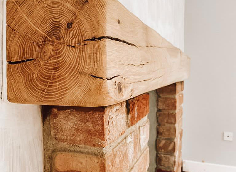 Rendered fireplace with oak beam and brick piers